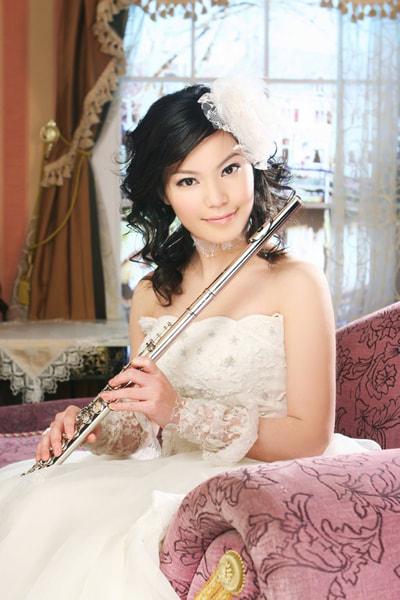 Sandy seated with her flute in a white dress